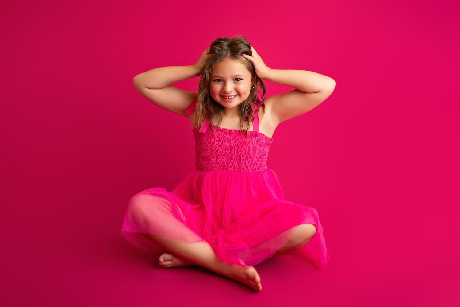 Joyful dance movements in bright pink tulle dress against magenta studio backdrop.