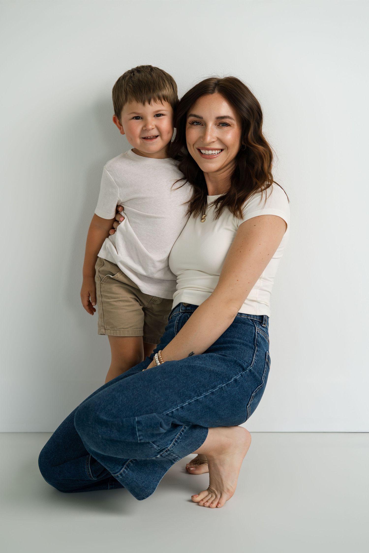 Candid family moment captured against minimalist white backdrop.