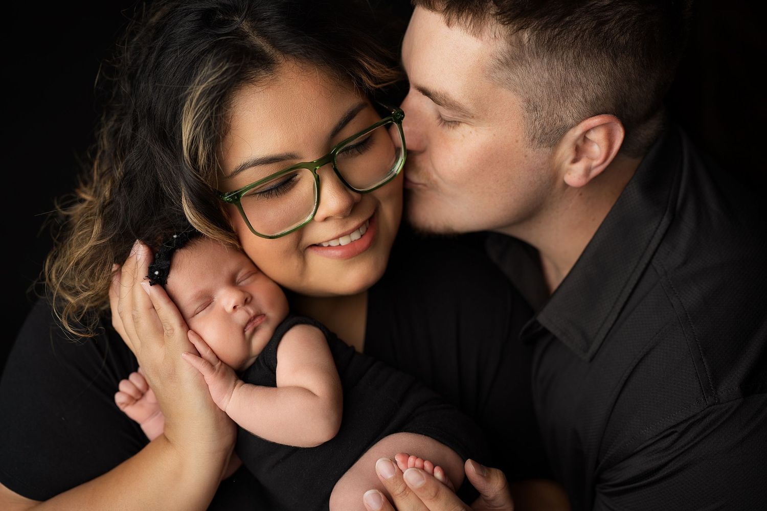 Intimate couple's portrait session with dramatic black backdrop and matching outfits.