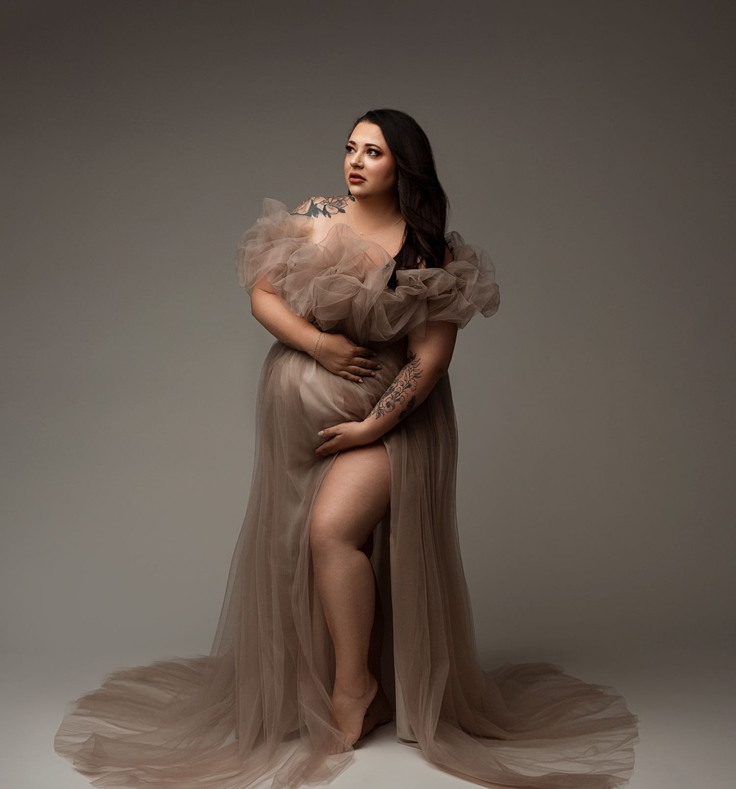 Romantic beige tulle gown with voluminous ruffled neckline photographed against neutral background.