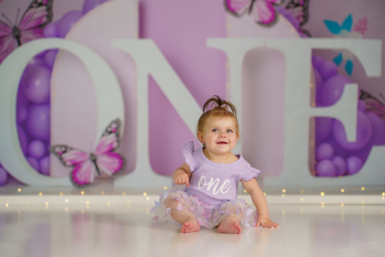 Purple themed photography studio with butterfly decorations and white flooring.