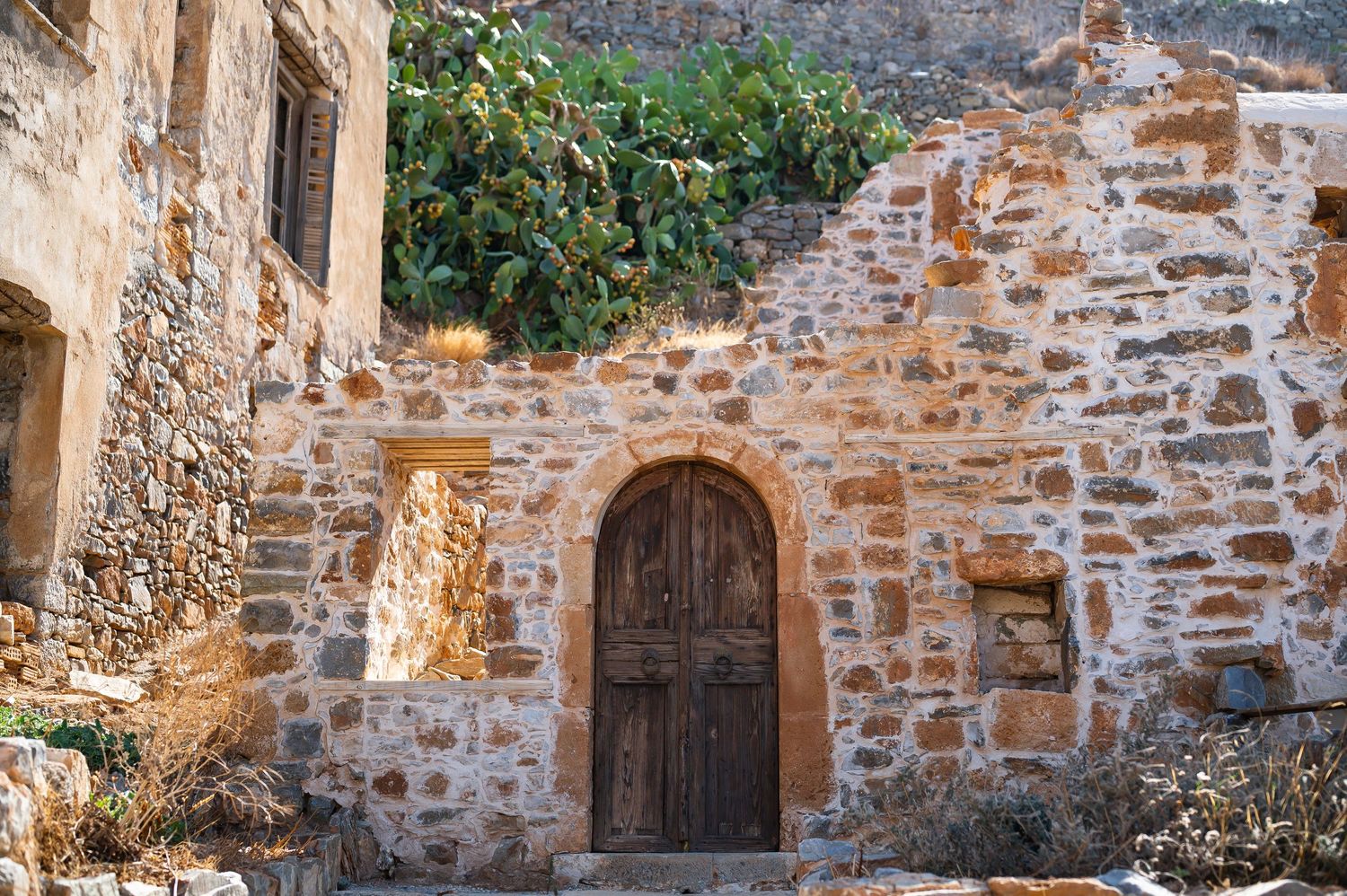 Ancient stone wall with wooden doors and rustic architectural details in Mediterranean style.