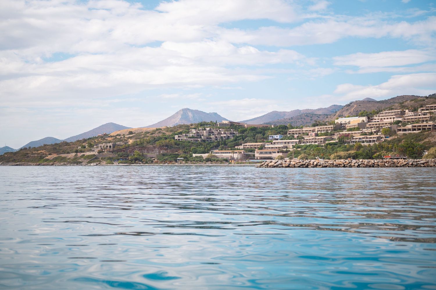 Panoramic view of a coastal mountain landscape with blue waters and rugged terrain along the shoreline.