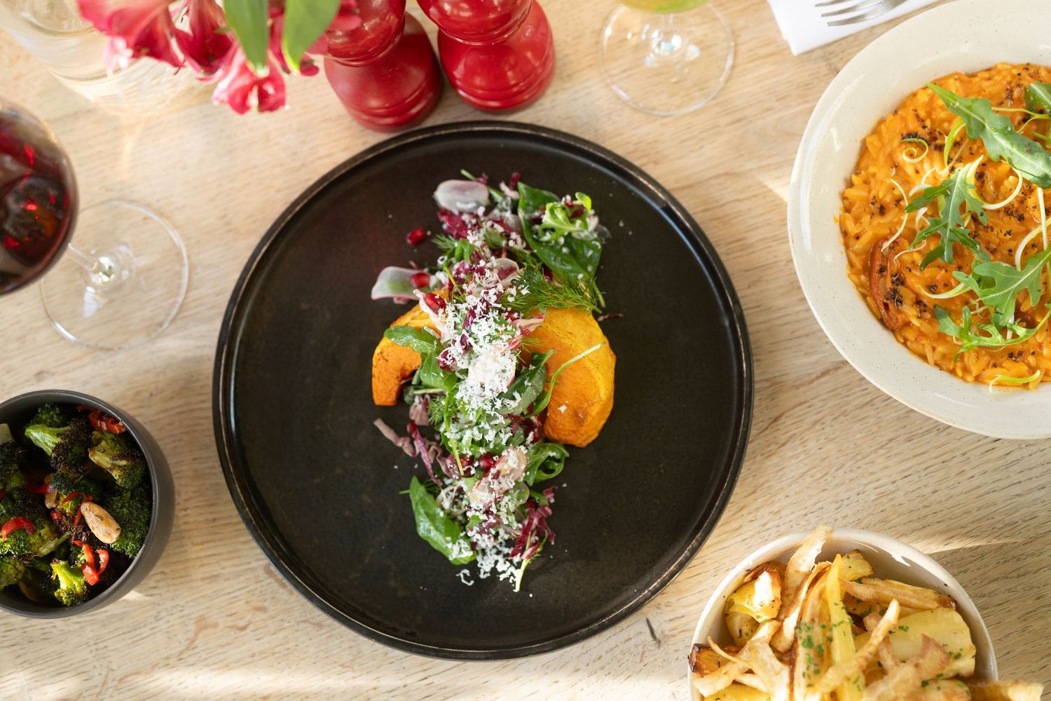 Elegant table setting with colorful plated dishes and wine glasses in natural light.