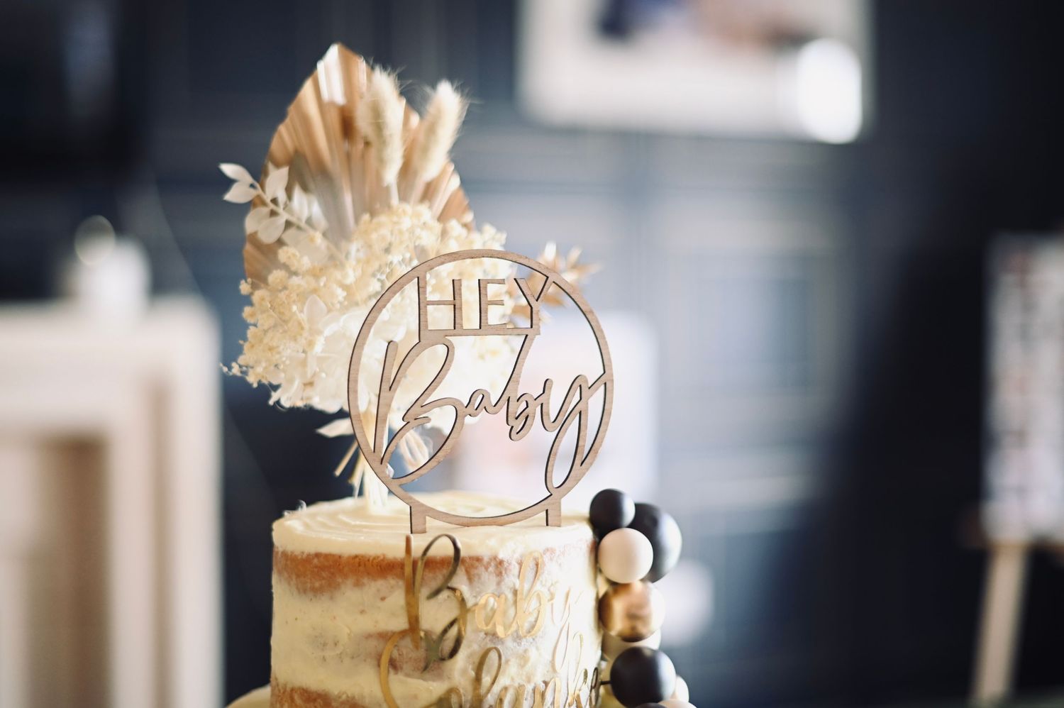 Elegant gold wedding cake topper with decorative text displayed on a dark background.