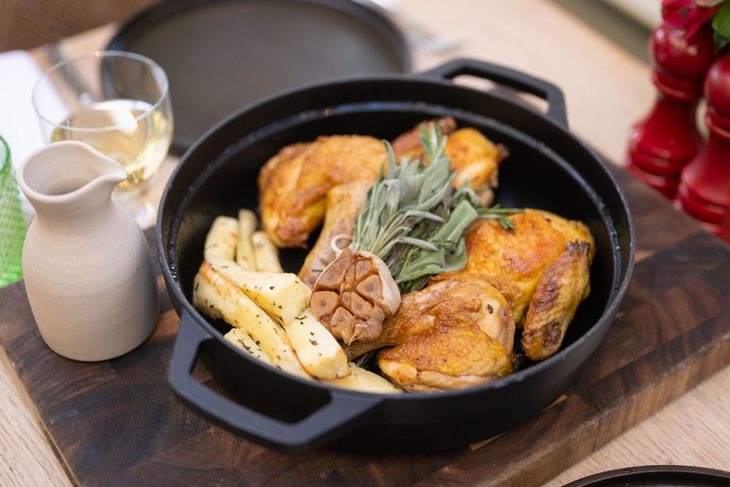Golden brown roasted chicken dish served in a cast iron skillet with herbs.