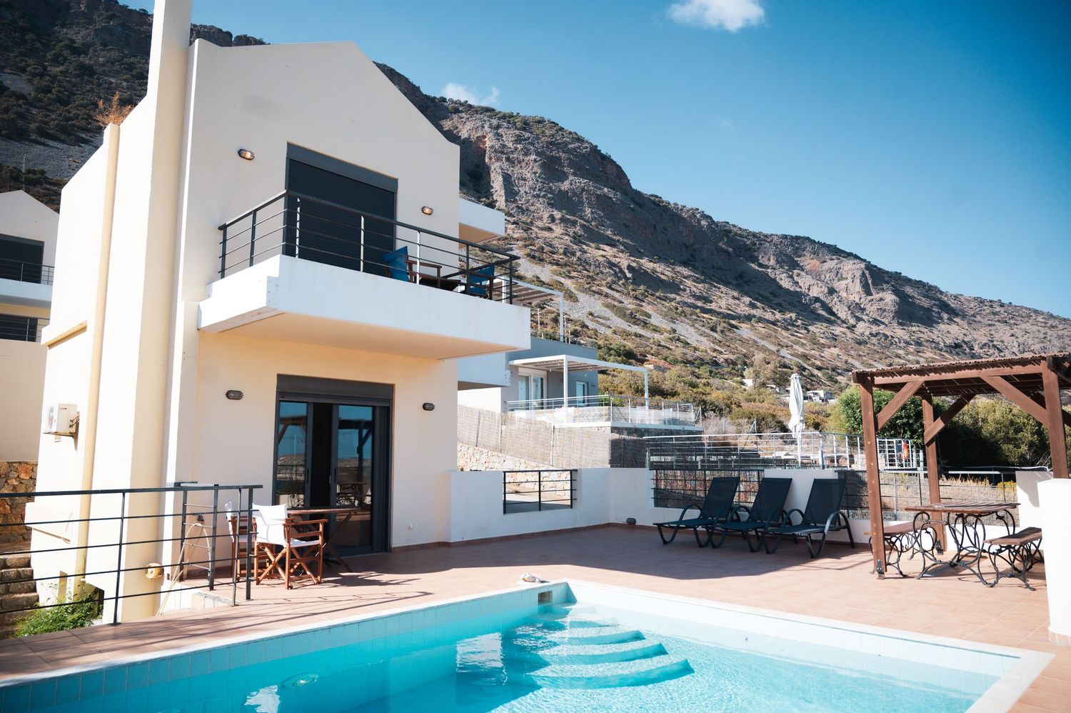 Modern white villa with swimming pool and mountain views in Mediterranean setting.