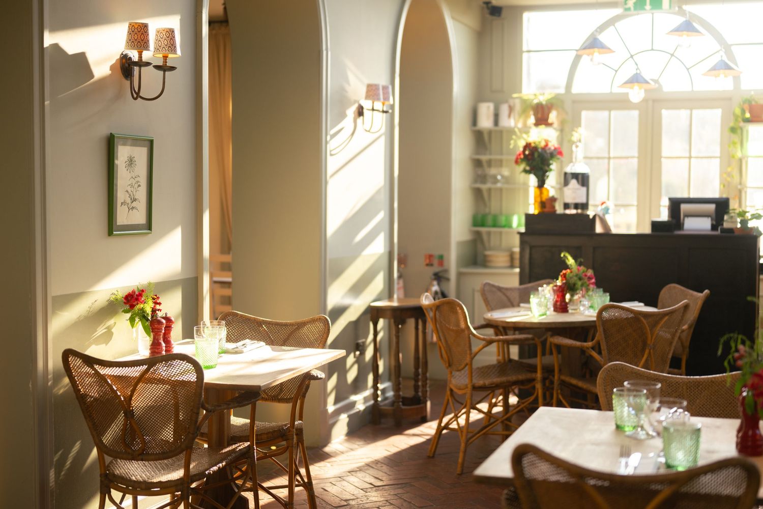 Sunlit dining room interior with wooden chairs and large windows.