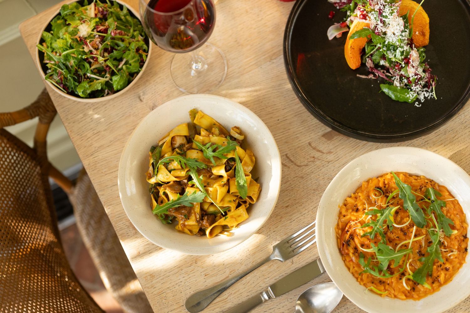 Gourmet pasta dishes garnished with fresh herbs served on dark and white plates.
