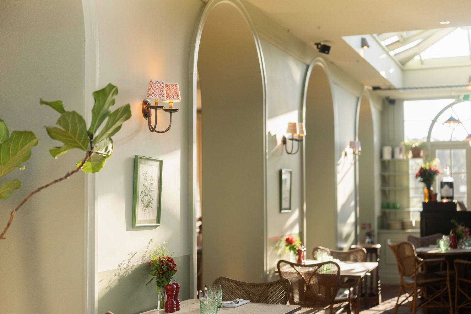 Bright sunlit dining room with white walls and modern decor featuring potted plants.