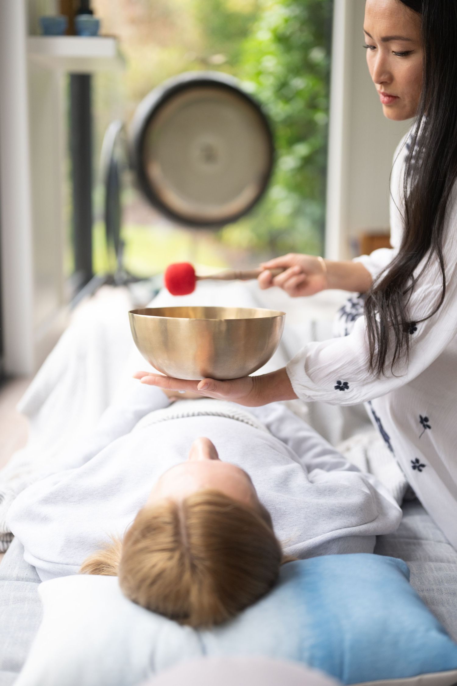 Sound therapy session with singing bowl and meditation tools in serene white setting.
