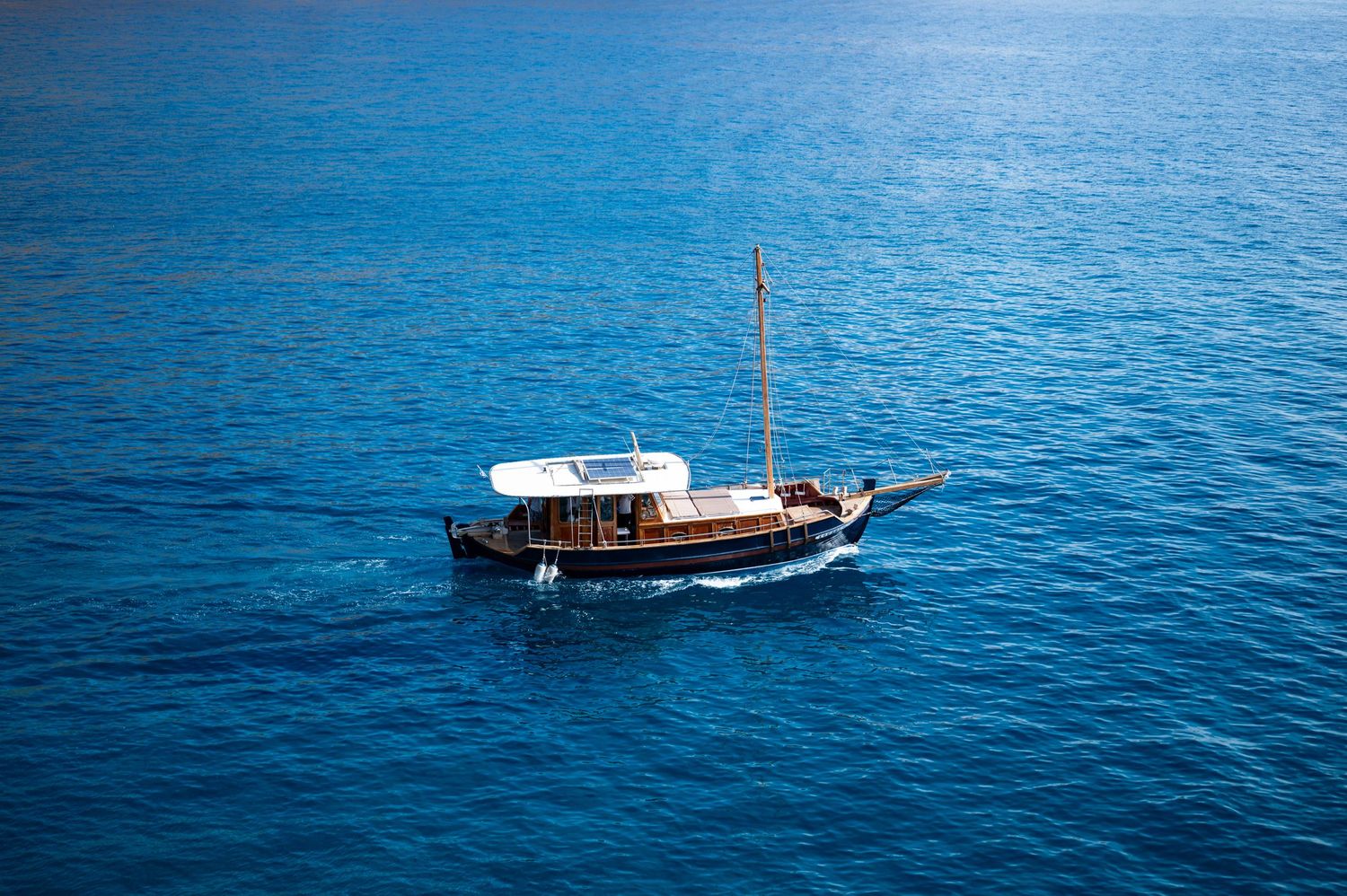 Traditional wooden sailing boats floating on calm blue Mediterranean waters with mountains in background.