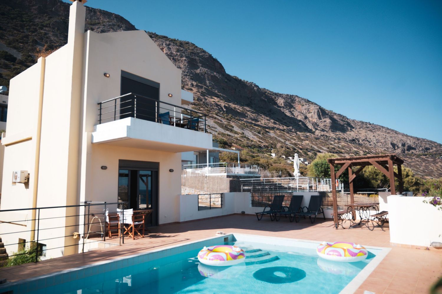 Luxury villa with infinity pool overlooking mountainous coastal landscape.