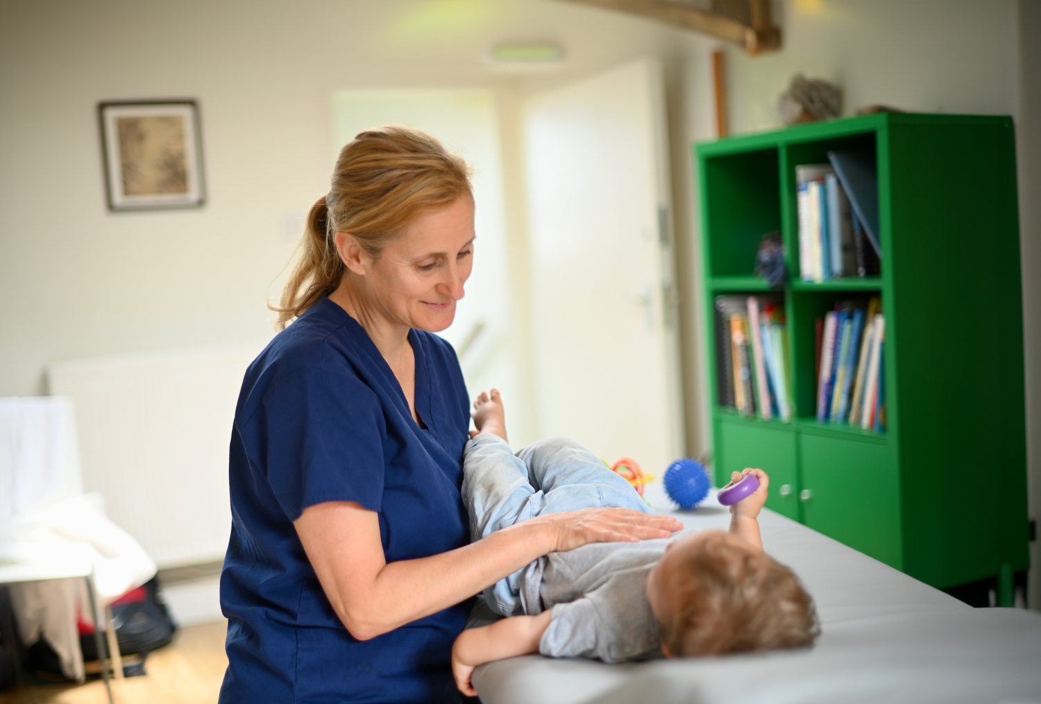 Medical professional working in a clinical setting with examination table.