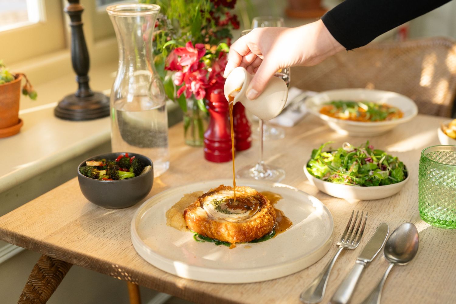 Elegant table setting with plates of gourmet food and wine glasses in natural light.