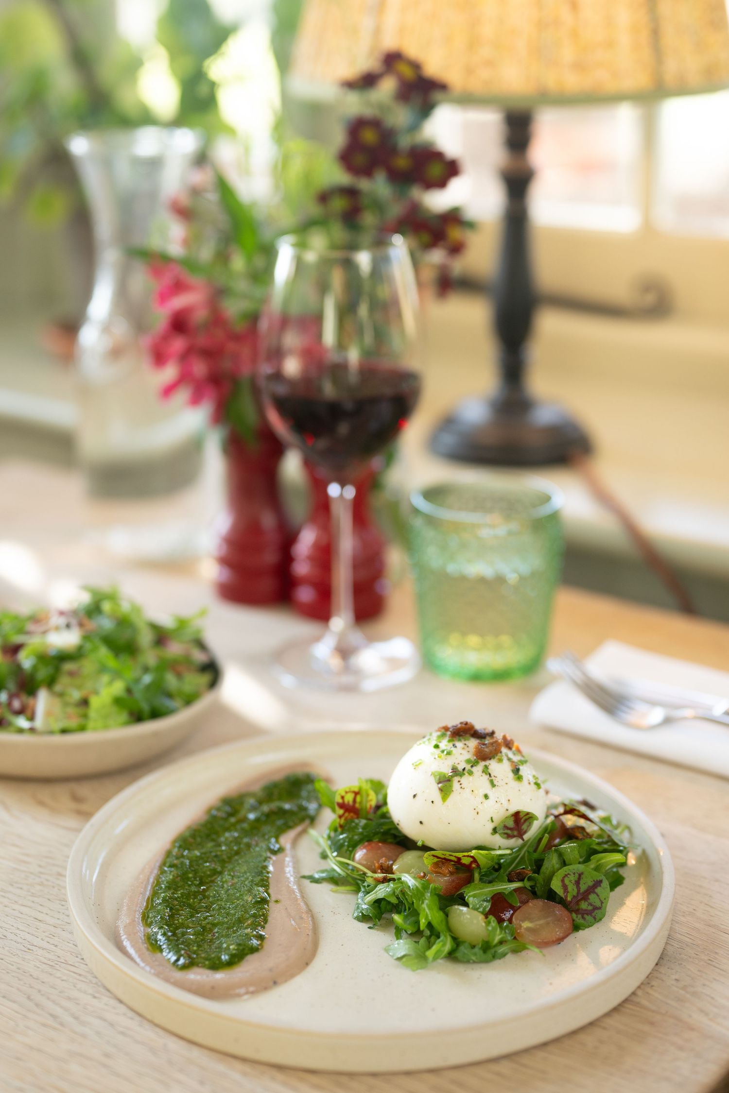 Artistically plated dishes with green garnishes and sauces on white plates.