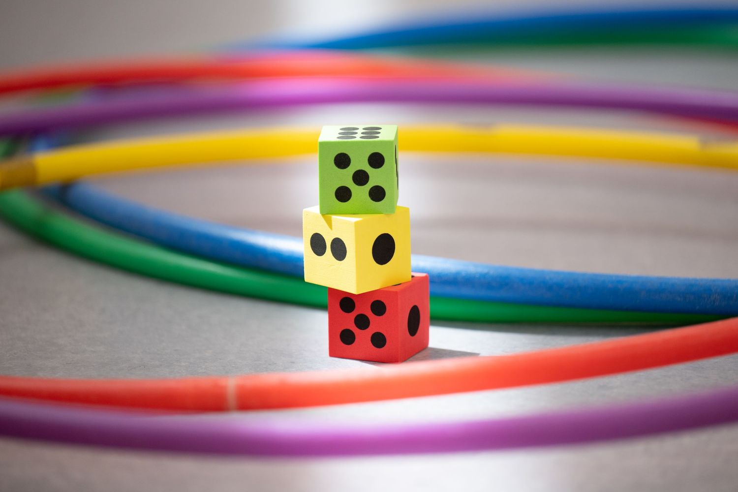 Colorful dice arranged in a line with vibrant hula hoops in the background.
