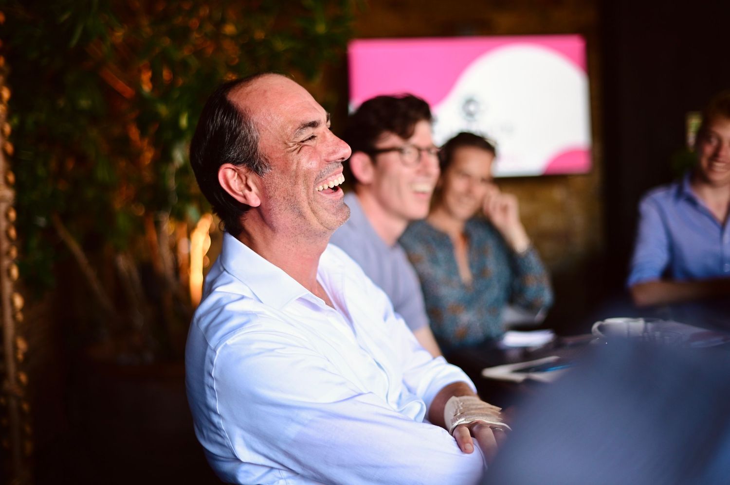 Group of attendees listening intently during a professional evening event with ambient lighting.