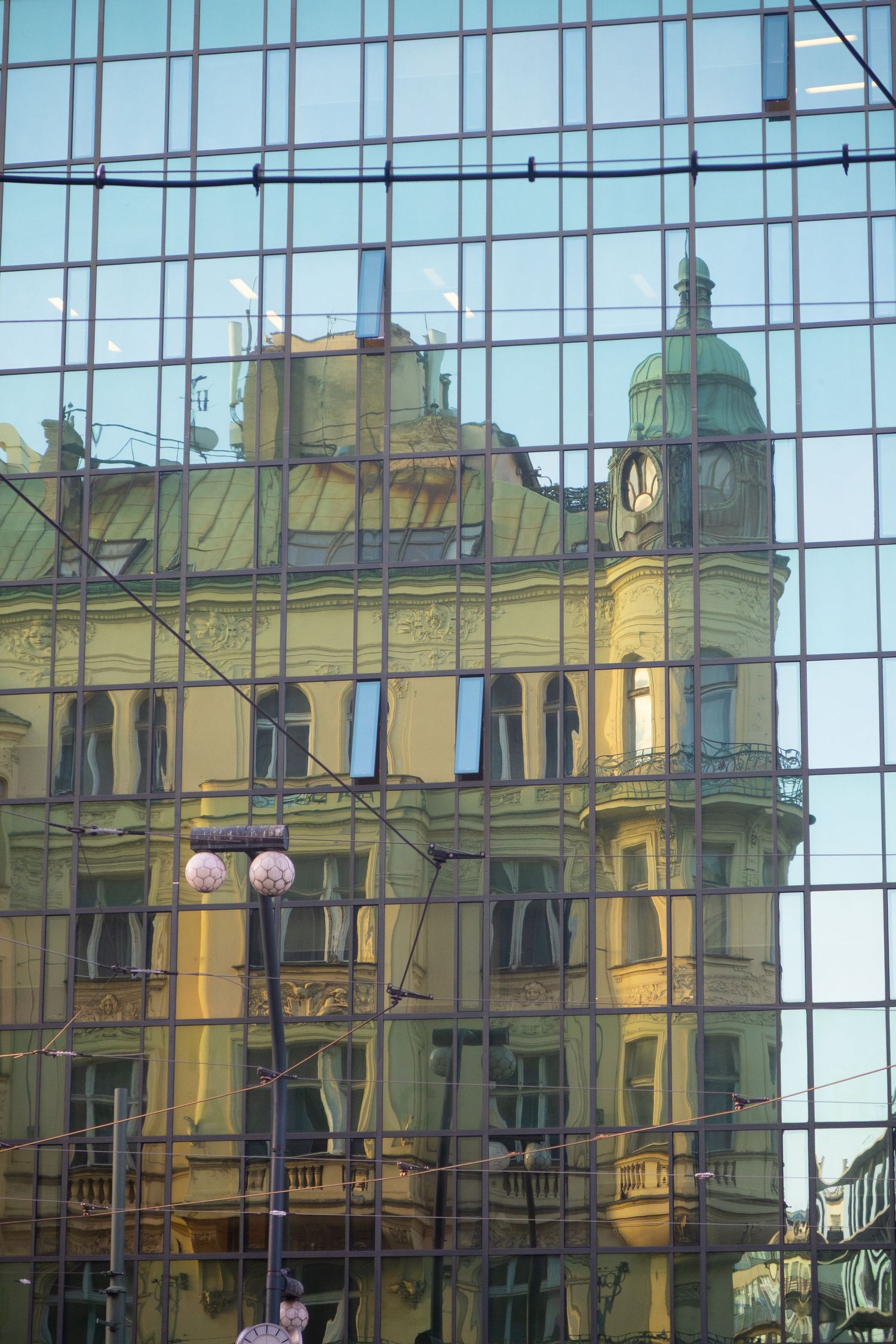 Yellow historic building facade reflected in modern glass windows.