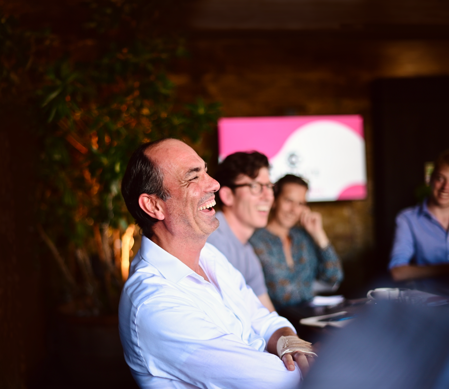 Business professionals engaged in discussion at a dimly lit conference or meeting.