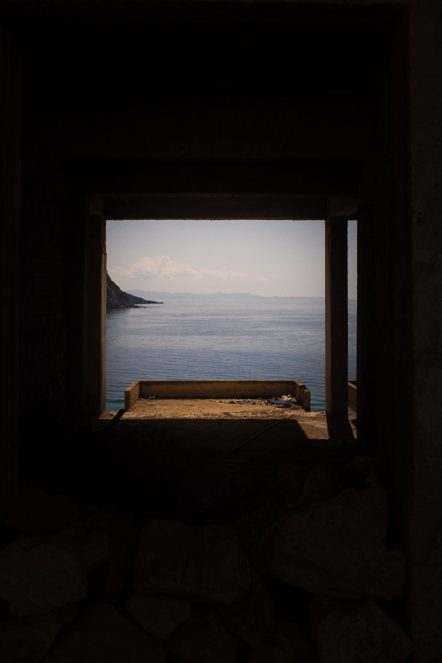 Panoramic ocean view framed through a dark window opening.