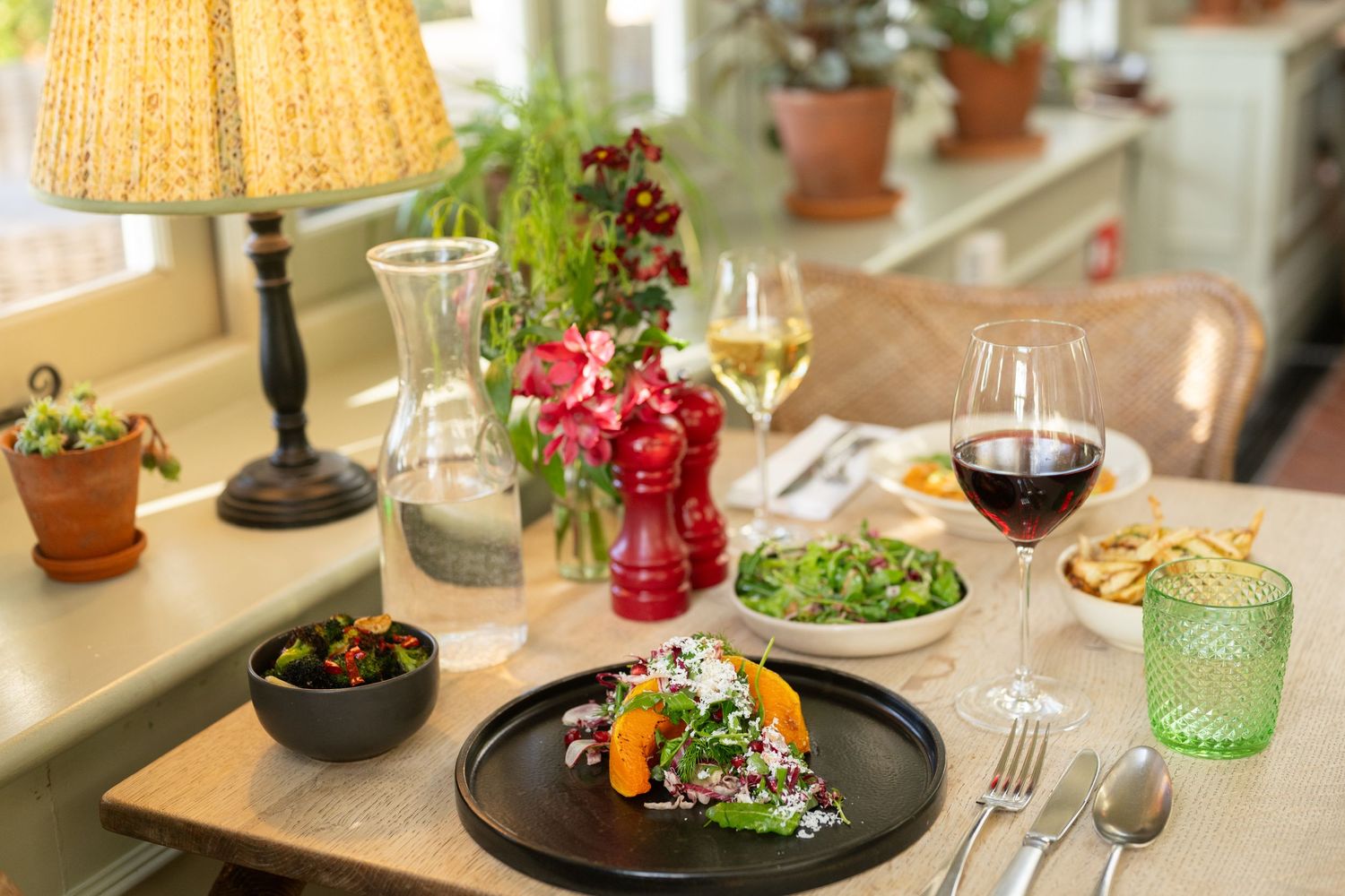Restaurant dining area with wicker chairs, table settings, and warm ambient lighting.
