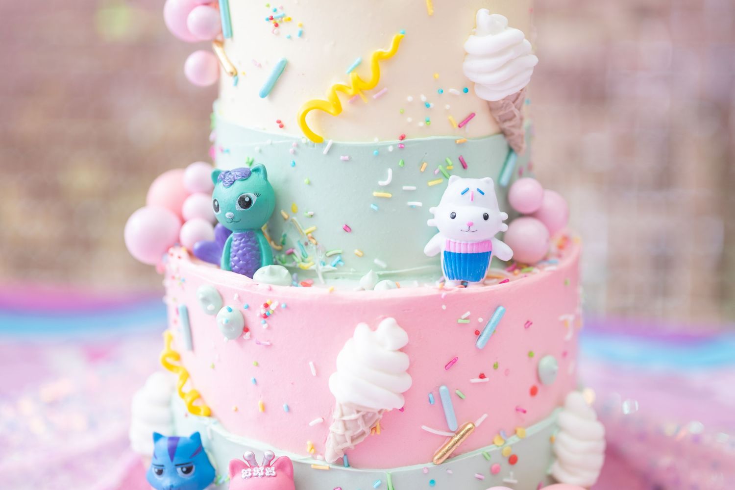 Pastel birthday cake decorated with unicorn theme featuring pink and blue colors and whipped cream details.