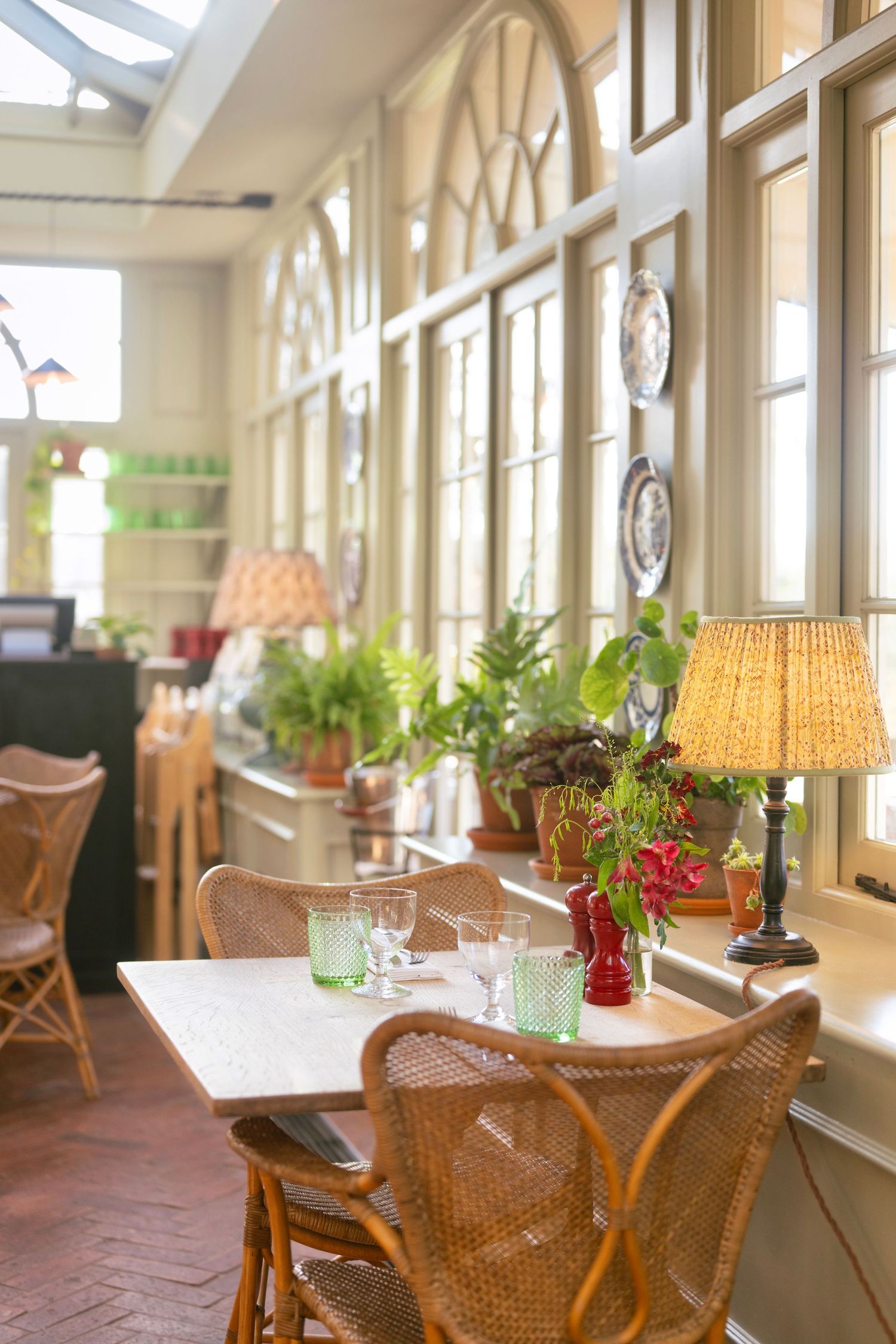 Elegant restaurant interior with wicker chairs and natural lighting streaming through large windows.