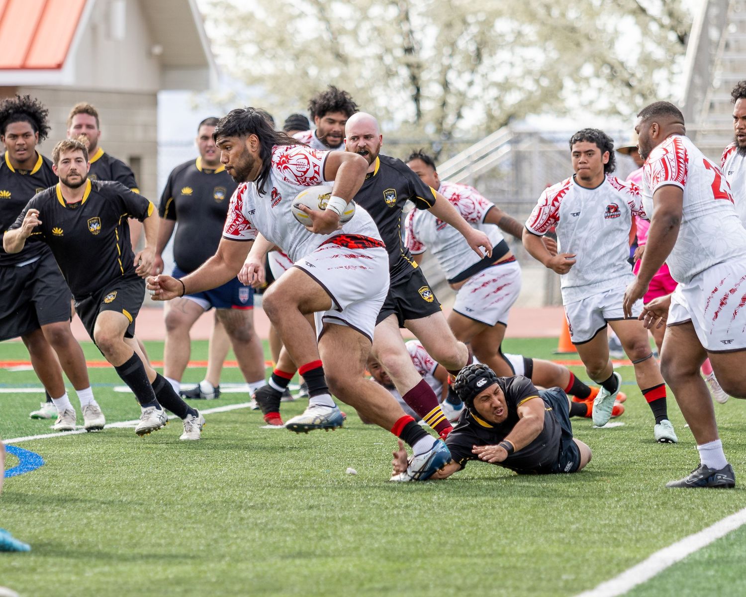 Rugby player breaks through a tackle attempt during a competitive match on turf field.