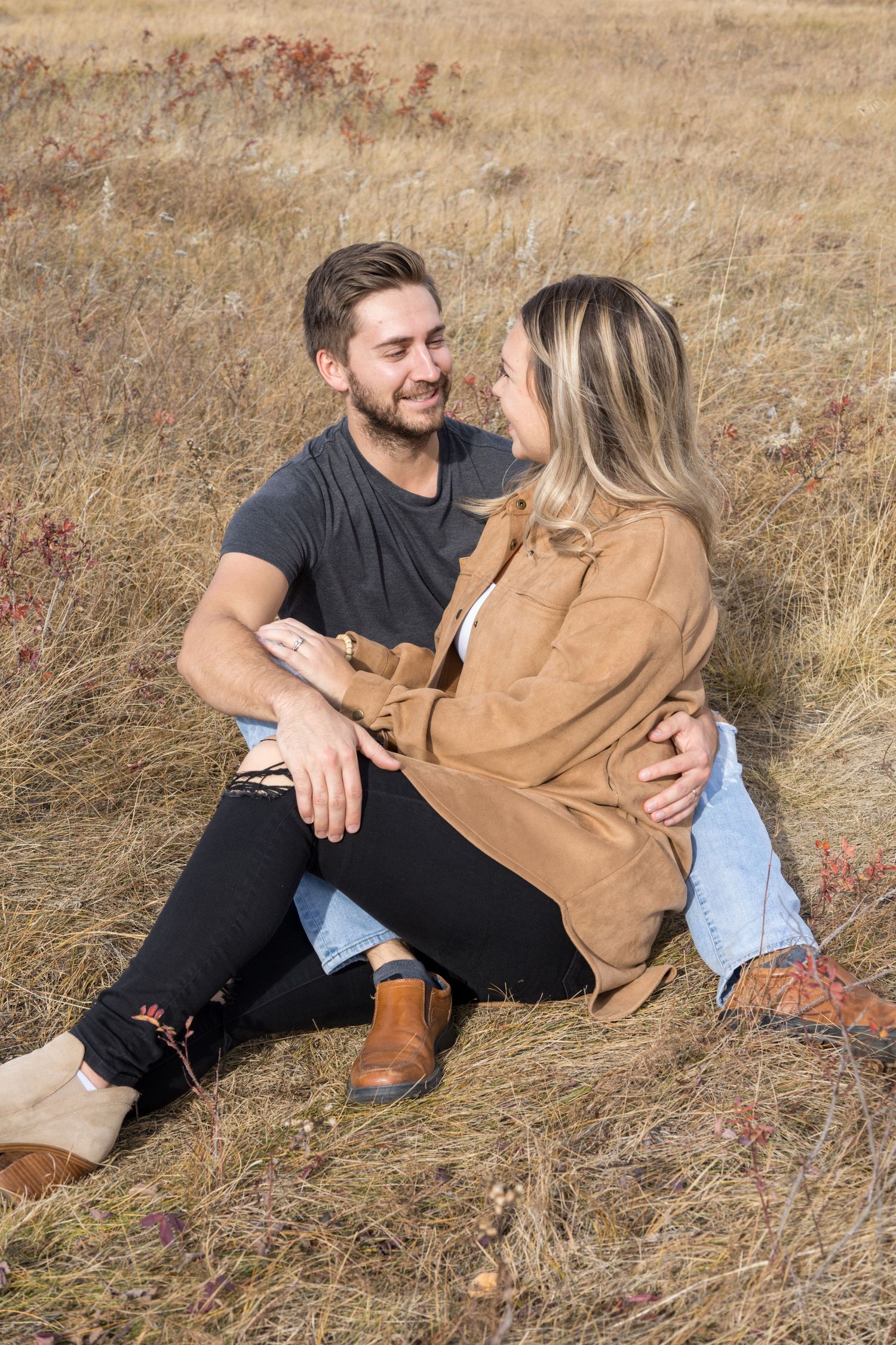 couple photoshoot sitting together in grass field