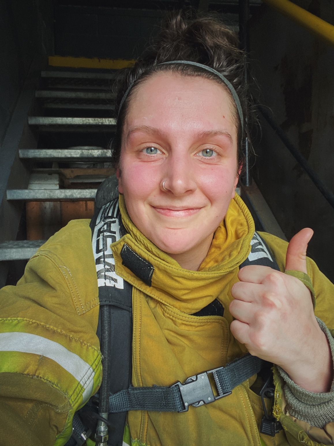 Firefighter in yellow protective gear and black beanie makes thumbs up gestures in a series of selfie photos.