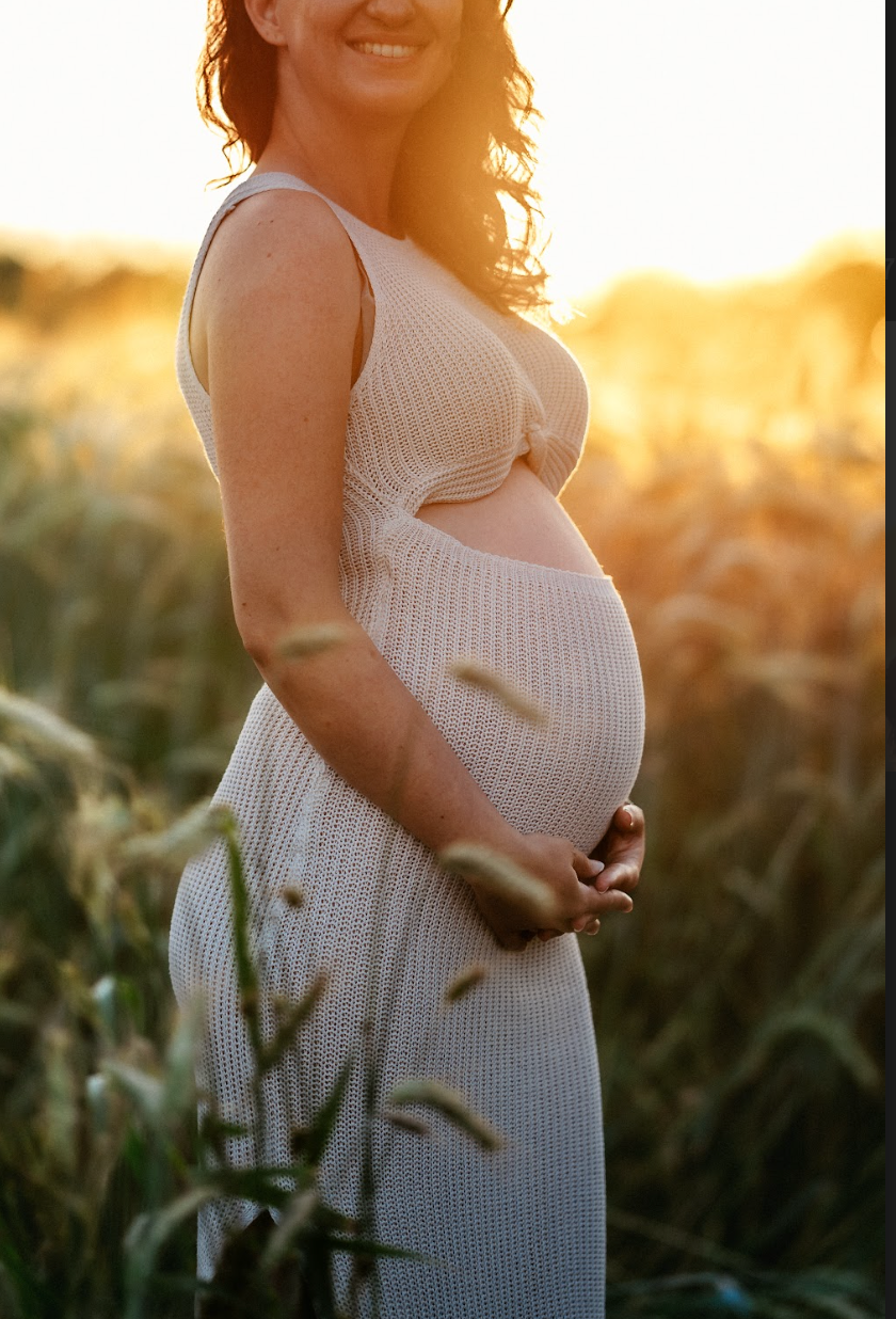 A tight profile crop focusing on a radiant maternal bump, capturing a gentle outdoor pregnancy session in Ljubljana's countryside.