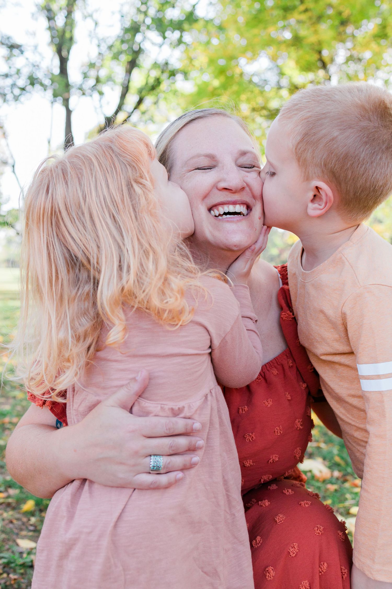 A heartwarming moment captured outdoors as children give sweet kisses in a park setting.