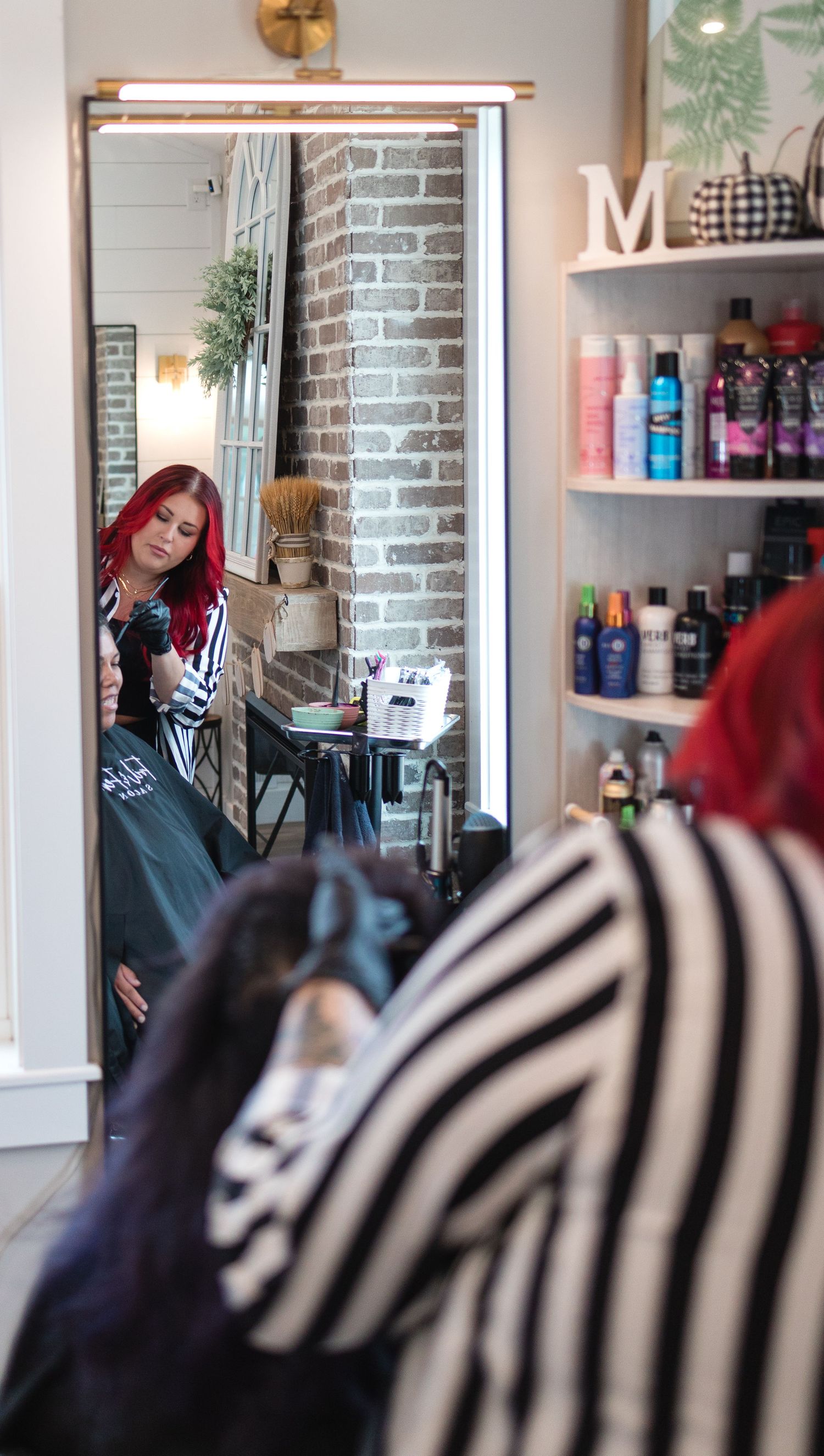Stylish salon interior with exposed brick walls and professional hair care products displayed on shelves.