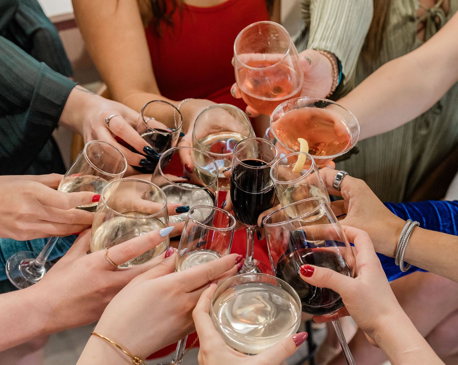 Multiple hands raising wine glasses for a celebratory toast.