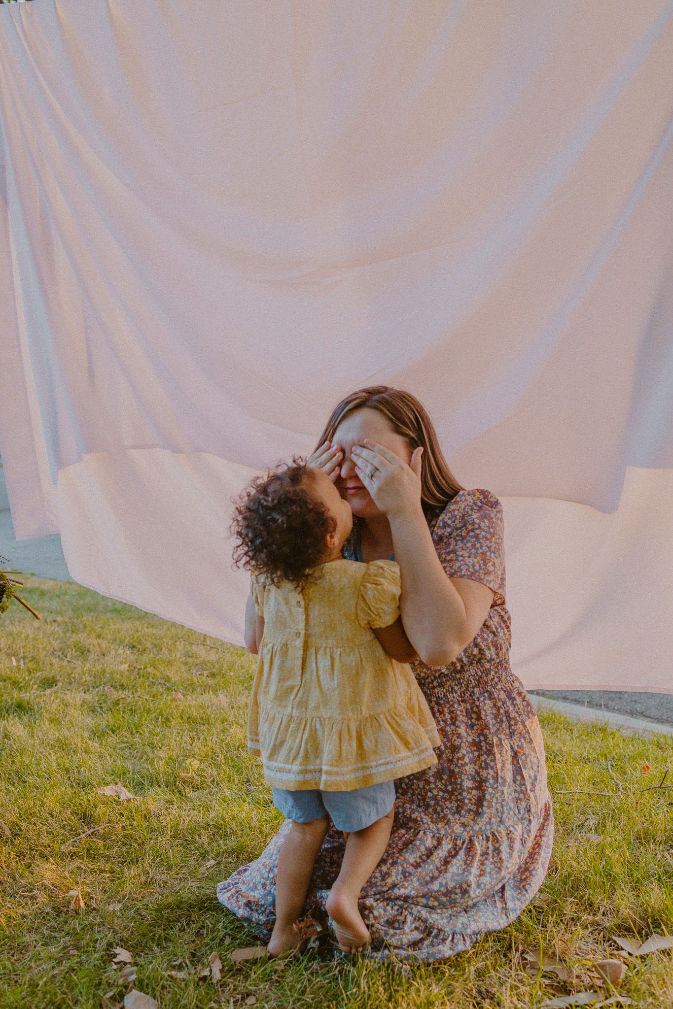 A tender moment shared between parent and child against a white backdrop outdoors.