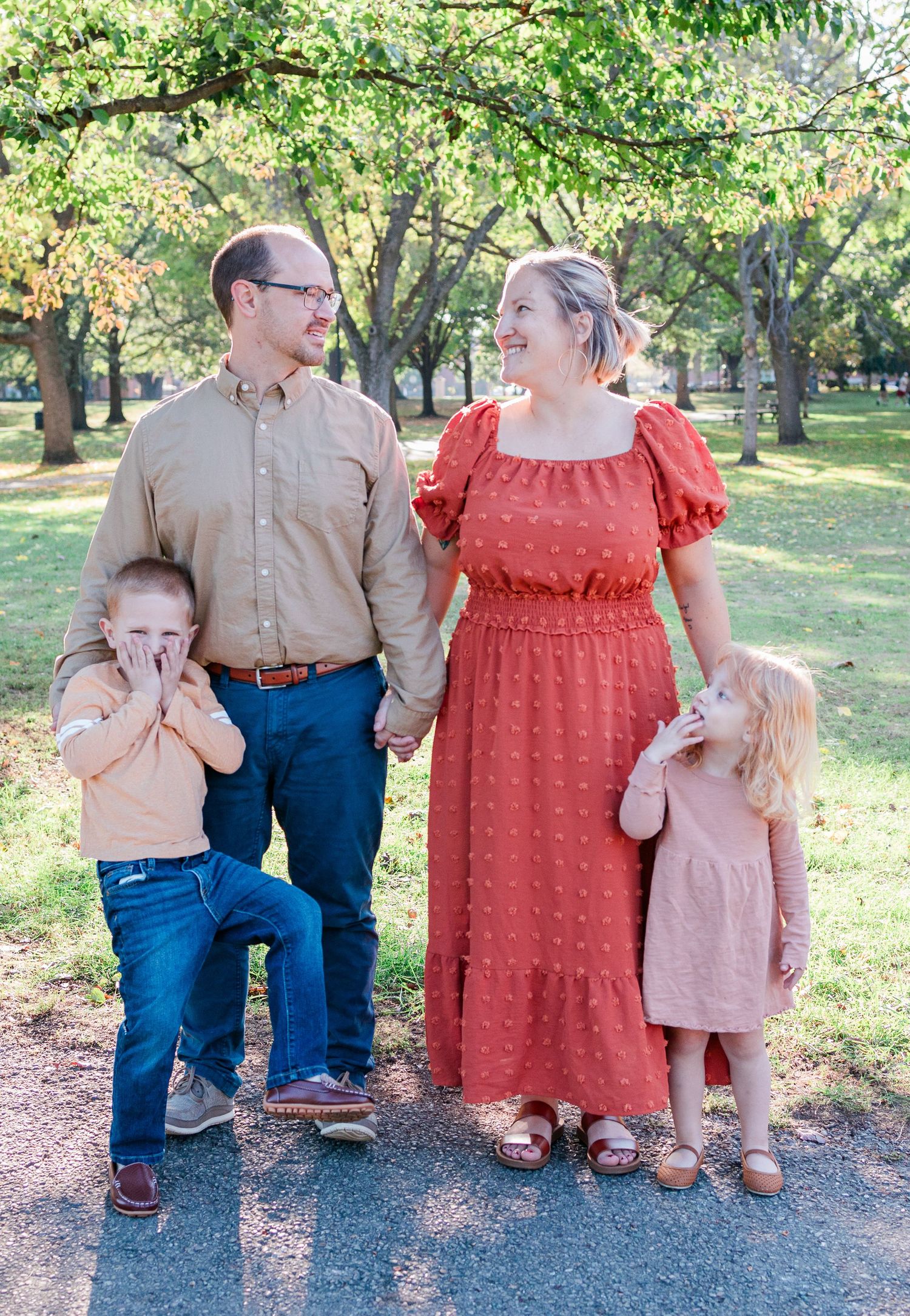 A family in coordinated fall outfits stands together during an autumn photo session.