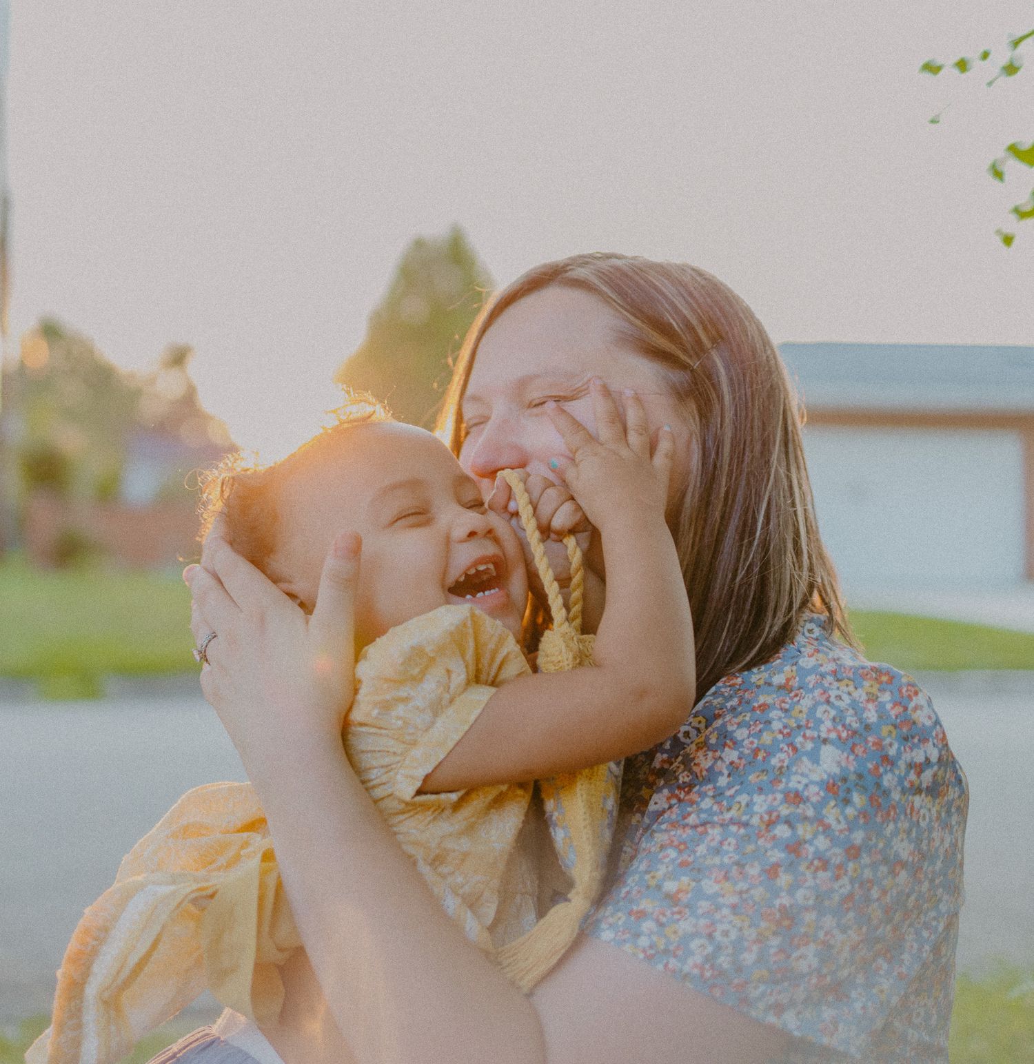 A joyful moment of laughter shared between parent and child against a sunset backdrop.