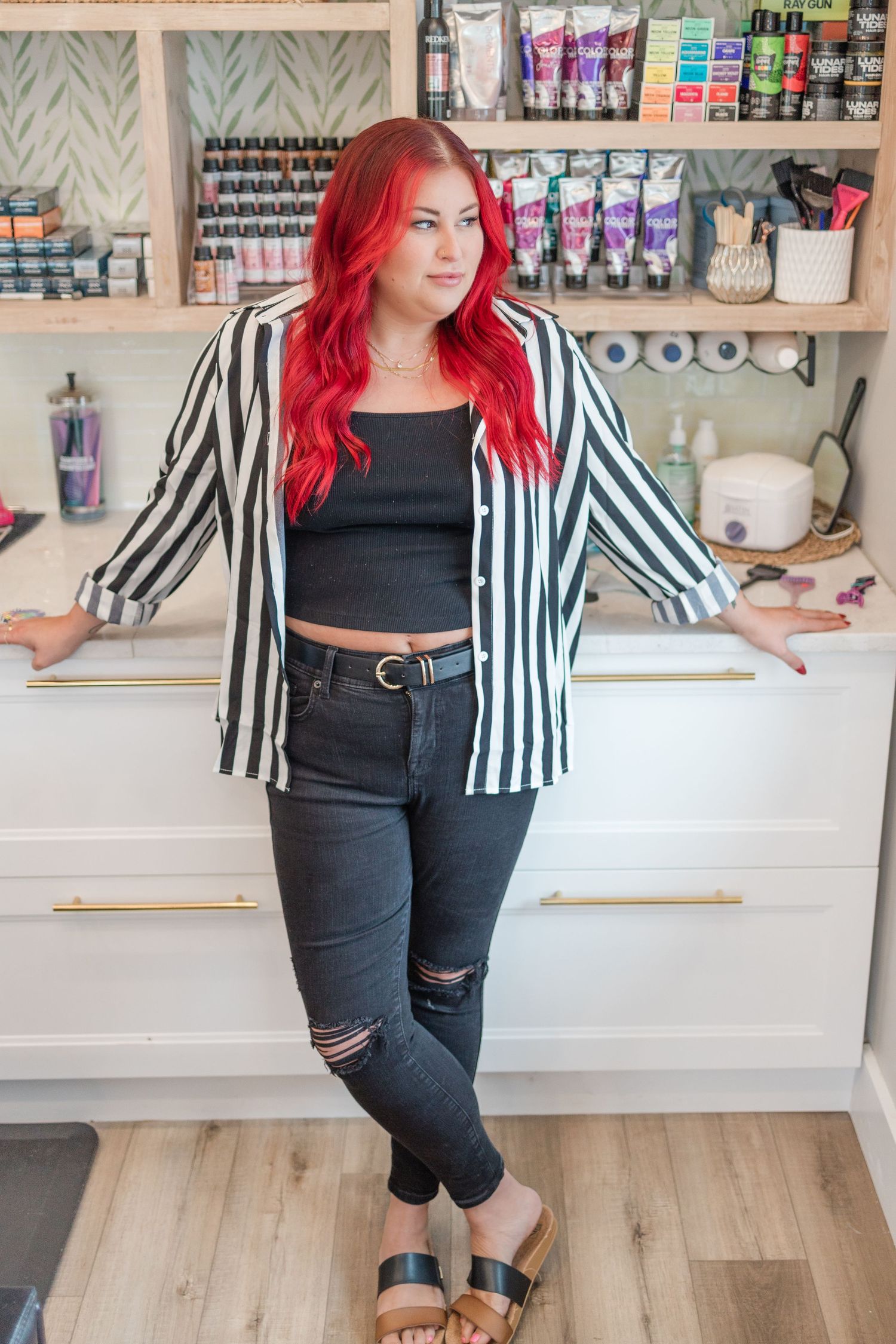 A striped black and white blazer paired with distressed black jeans creates a casual yet polished look in a beauty salon.
