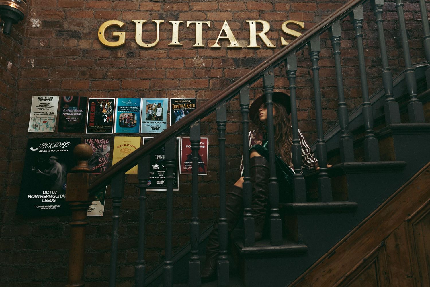 Woman sat under Guitars sign