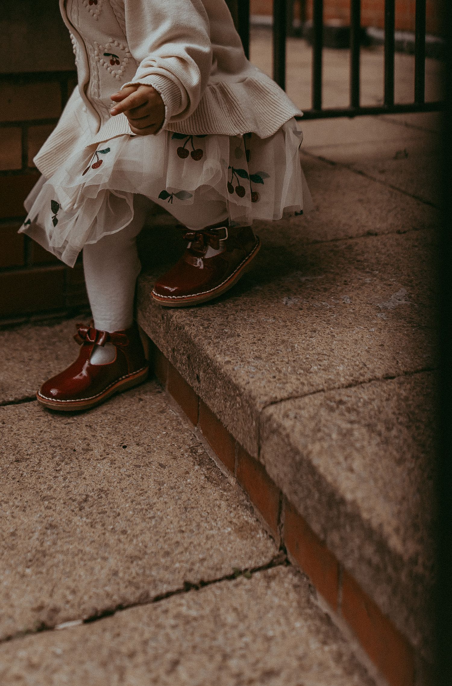 Child taking steps in red shoes in City