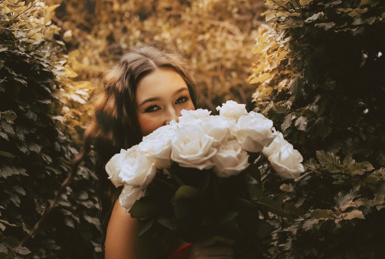 Woman smiling behind bouquet of white roses