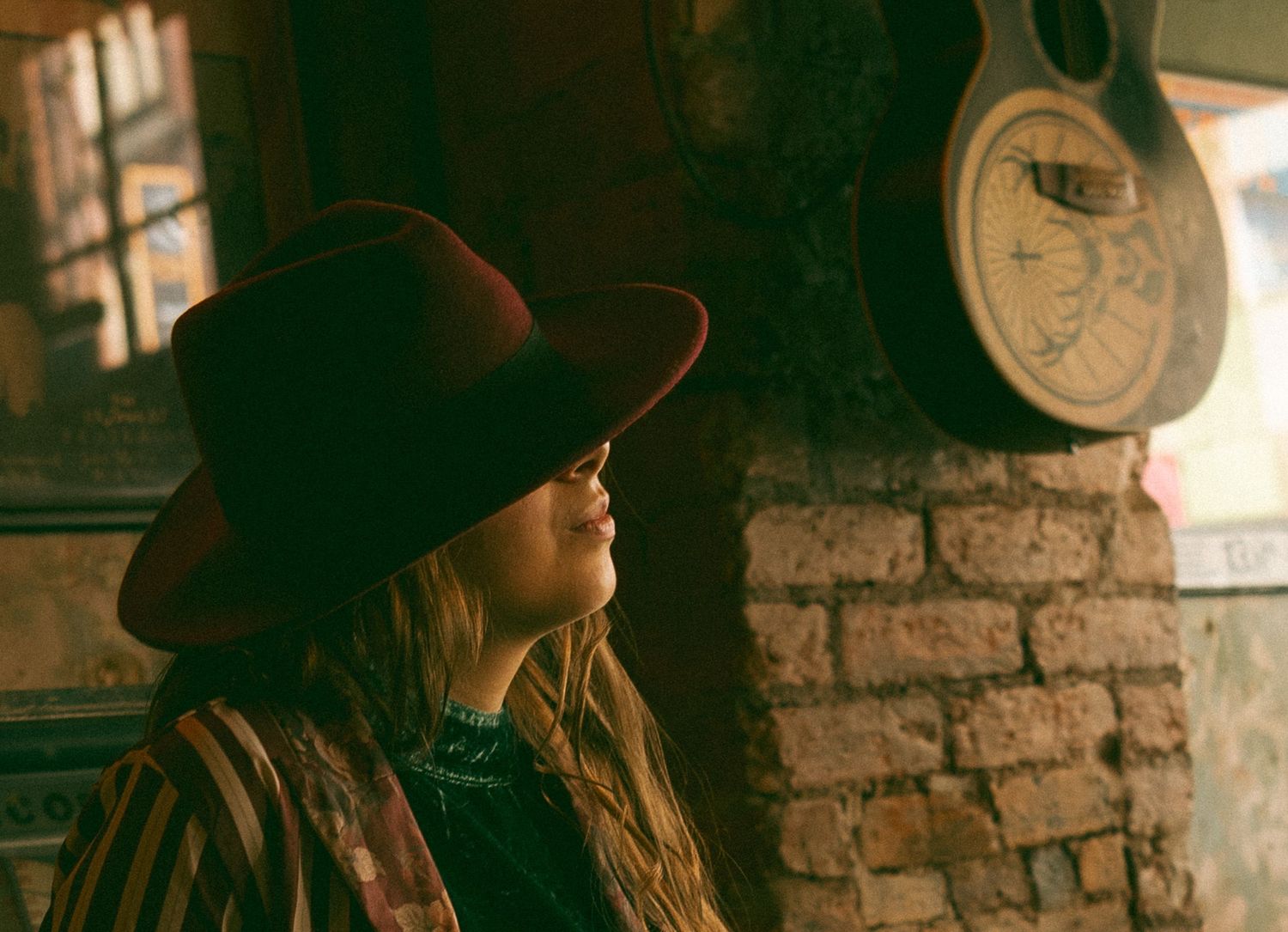 Woman looking into distance with guitar on wall