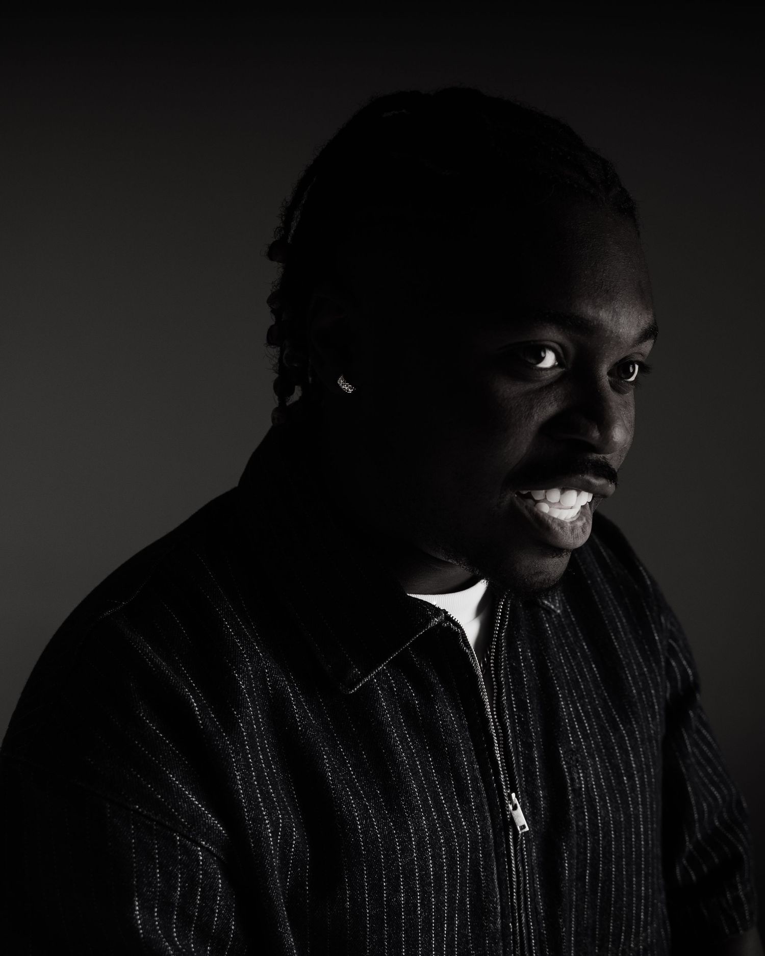Dramatic low-key portrait of a man in a black striped jacket against a dark background.