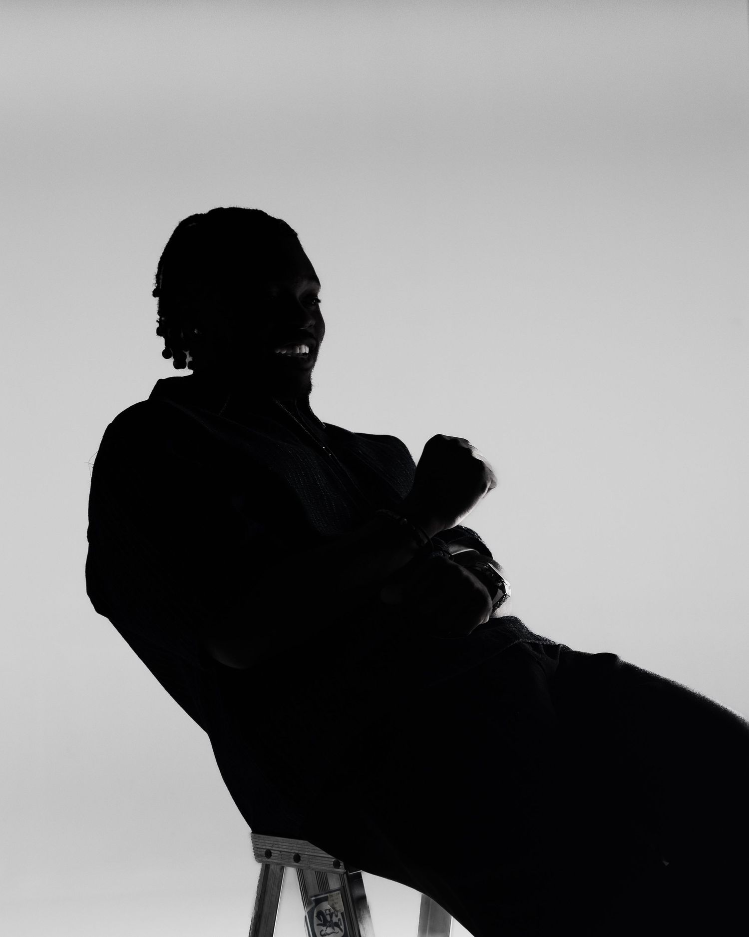 Black and white silhouette of a seated person with arms crossed against a light background.
