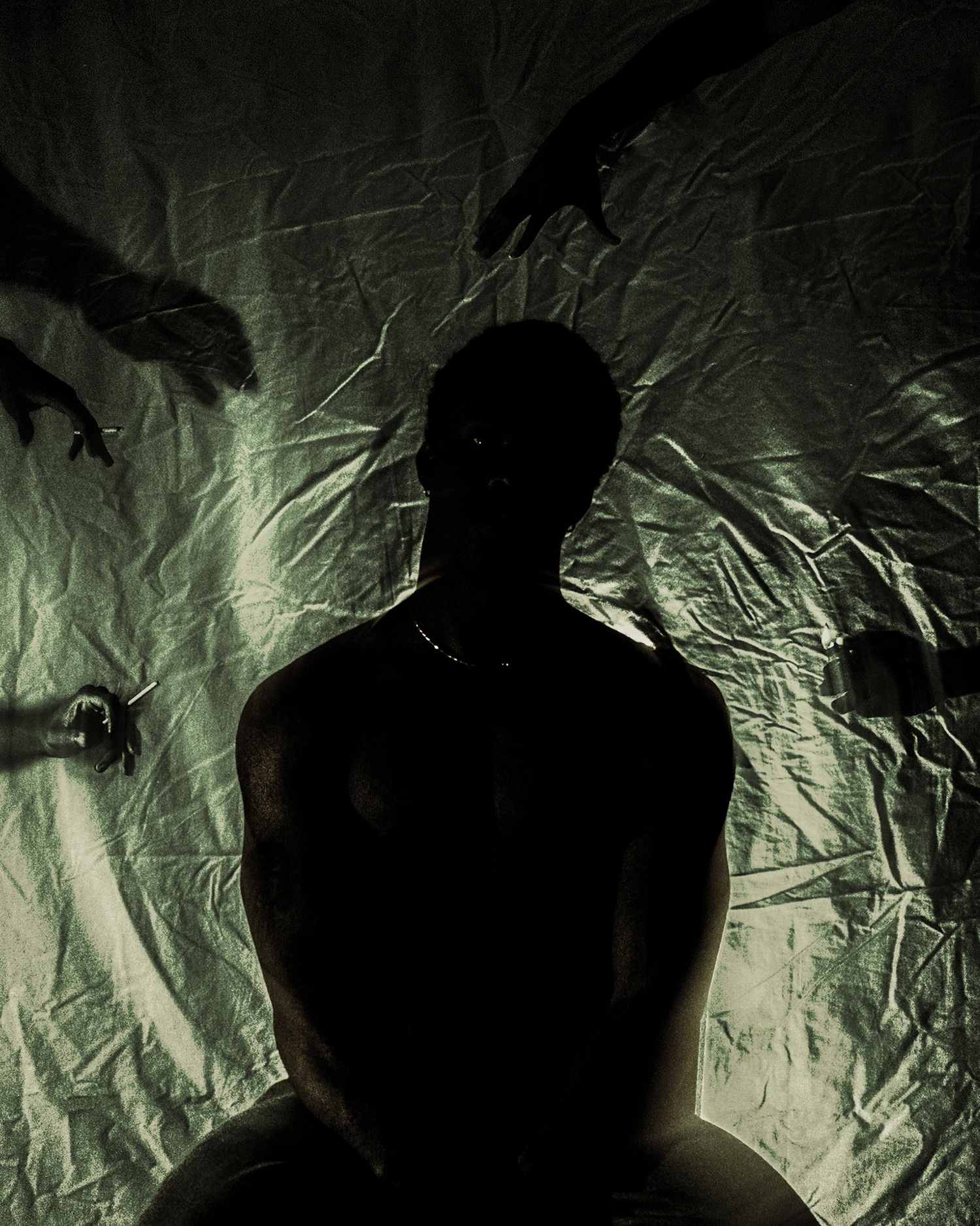 Dark silhouette of seated person with shadowy hands reaching from background.