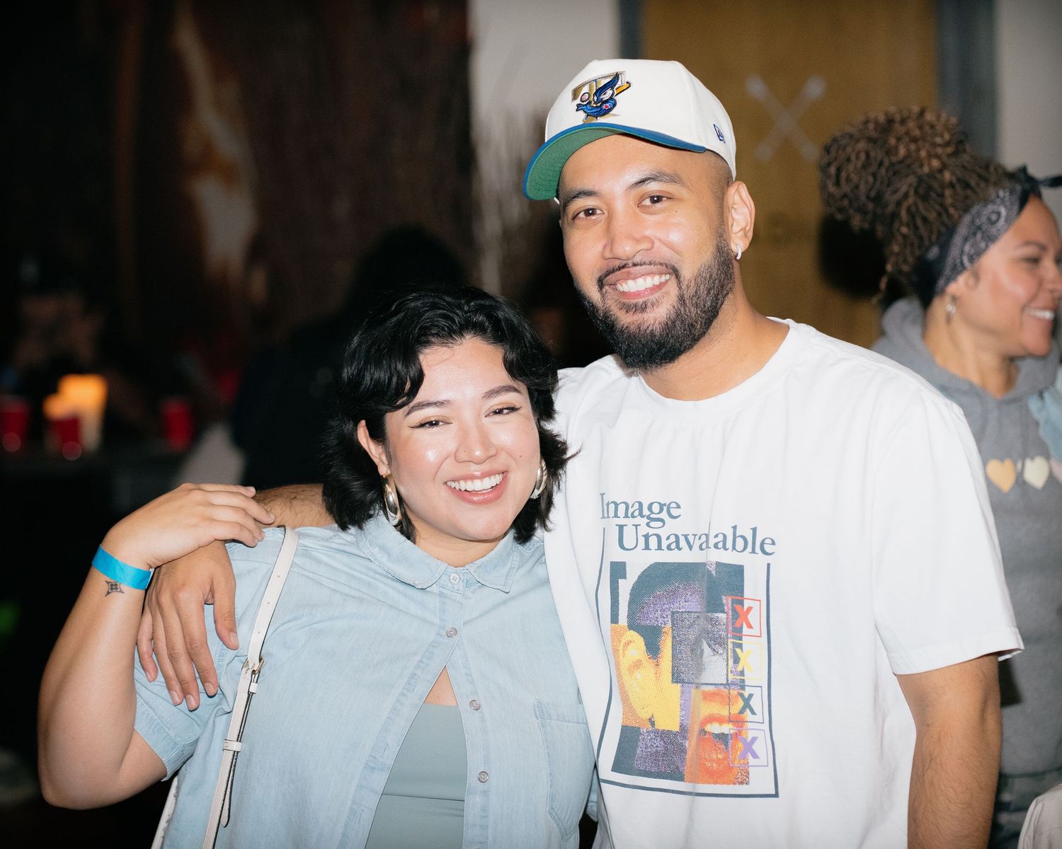 Smiling young woman and man pose together at a casual indoor social gathering or community event.