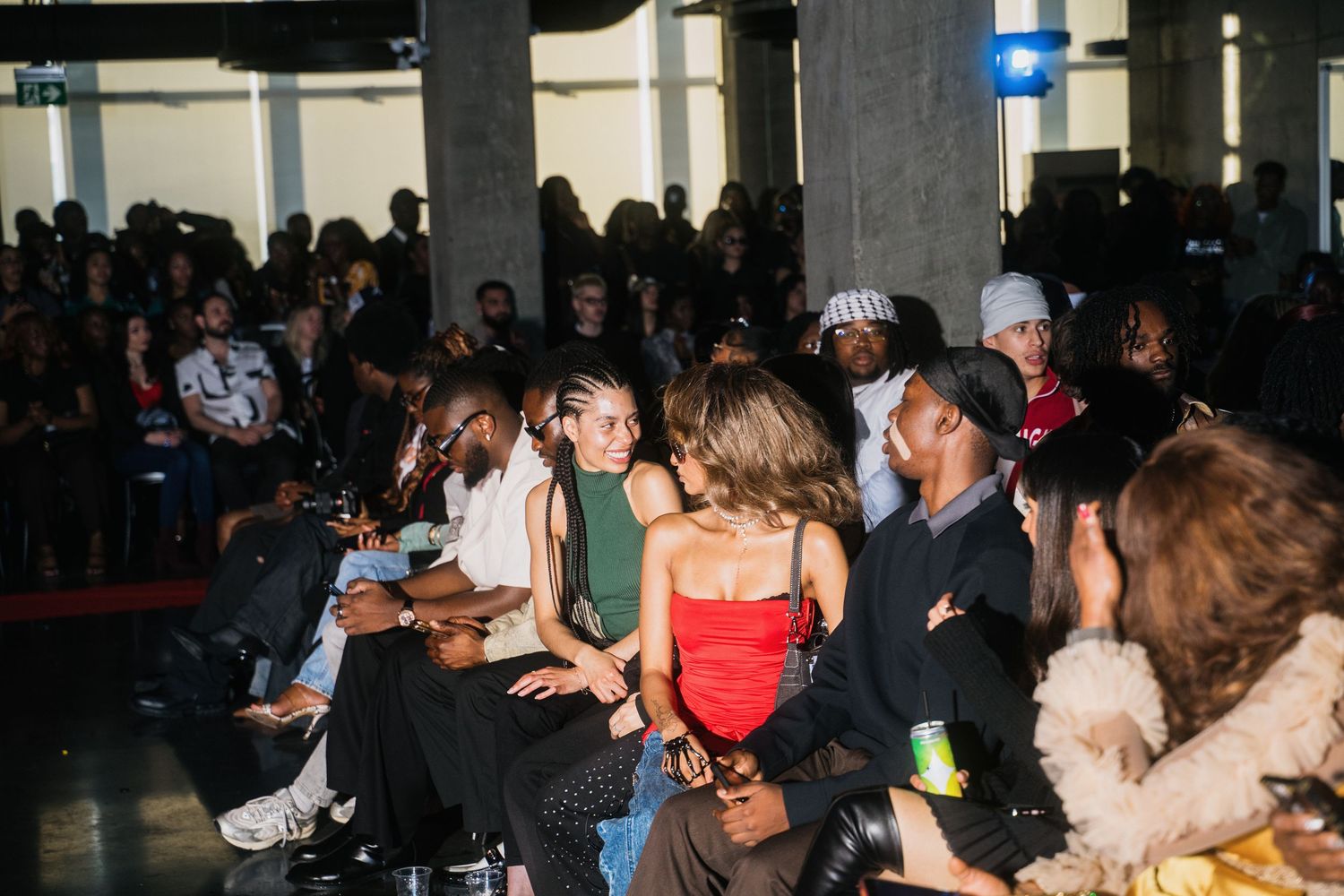 Diverse crowd of people sitting and socializing at an indoor fashion show event.