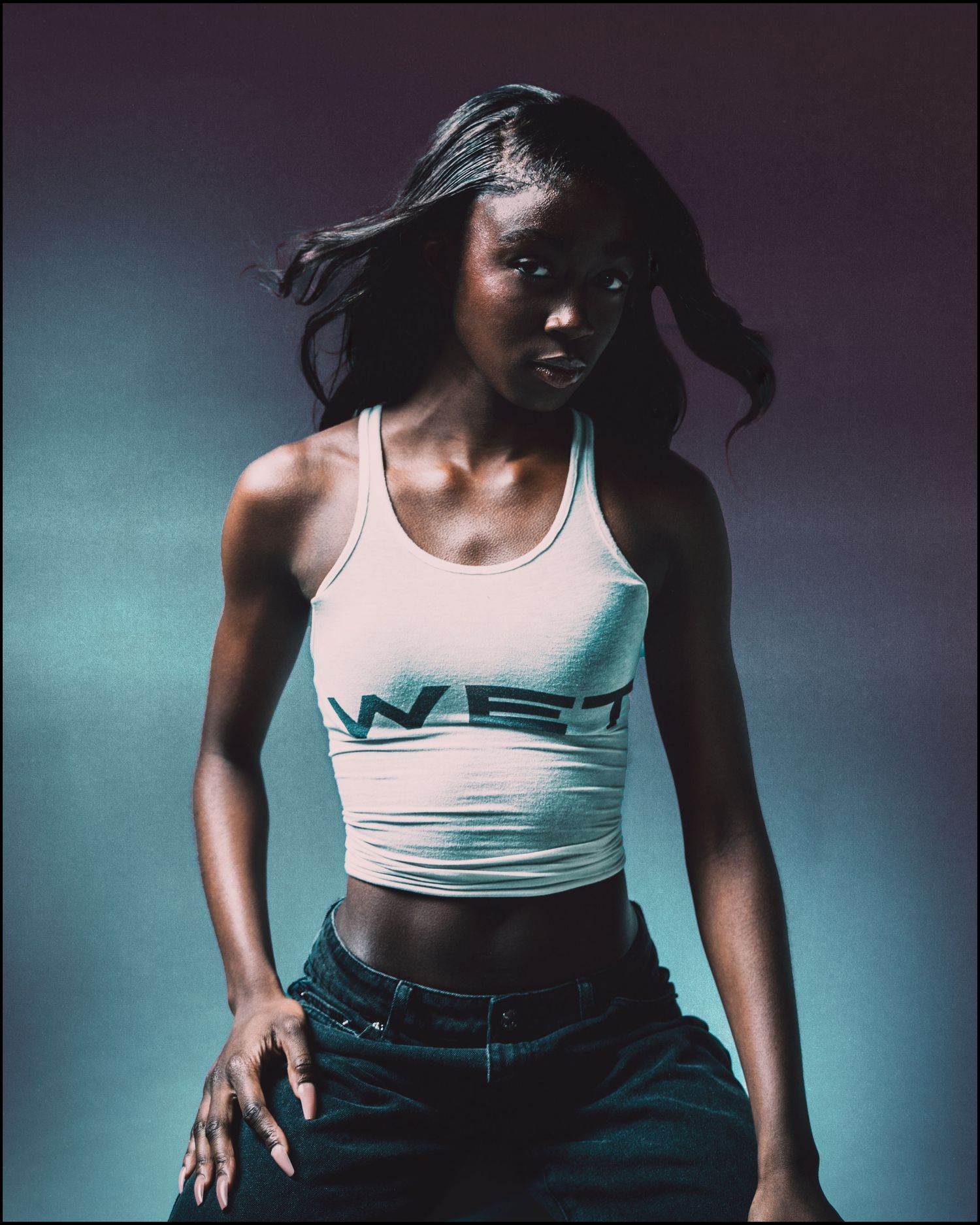 Woman in white WE1 crop top and jeans posing against blue-purple gradient background.