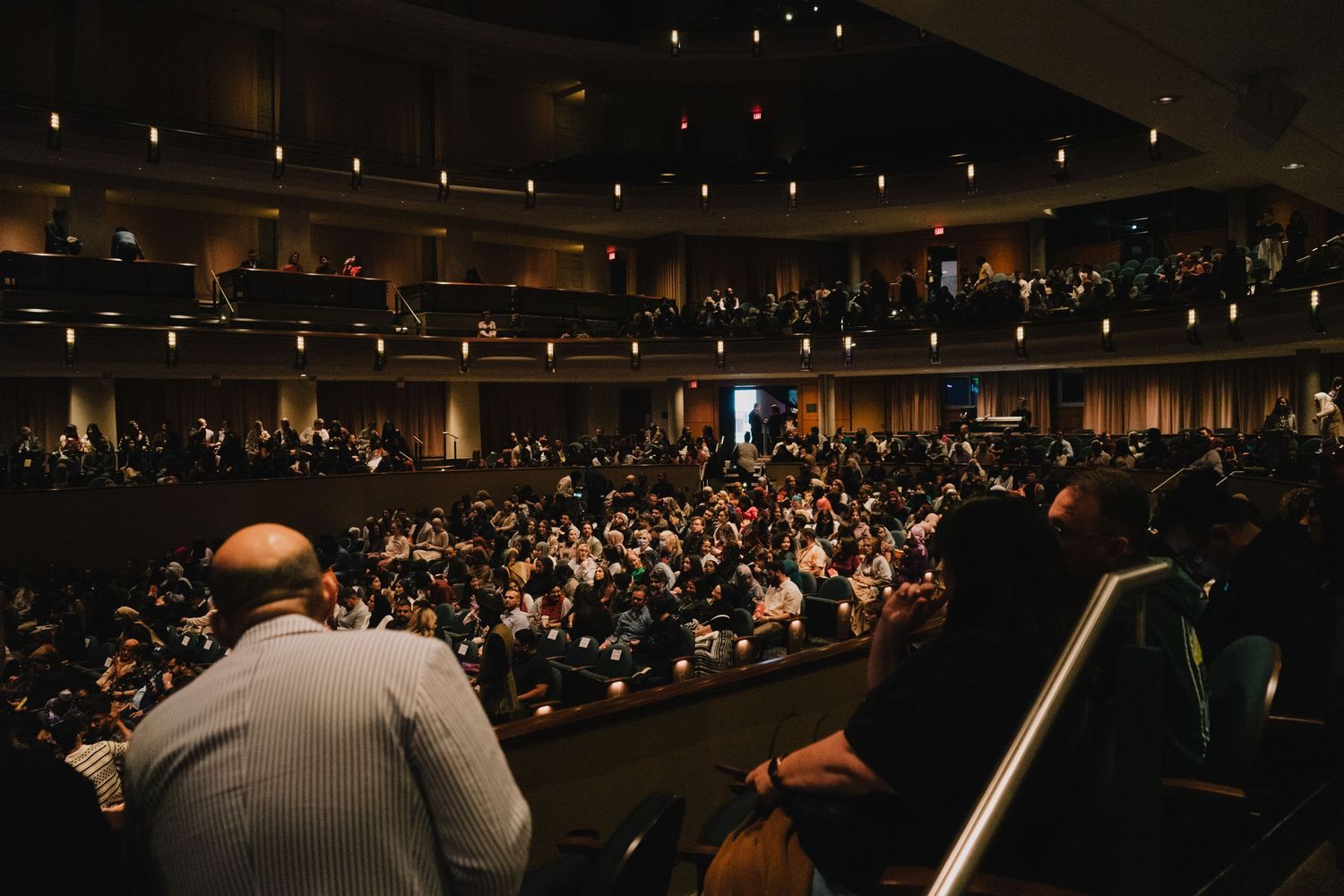 View from backstage of a large packed auditorium audience during a live performance event.